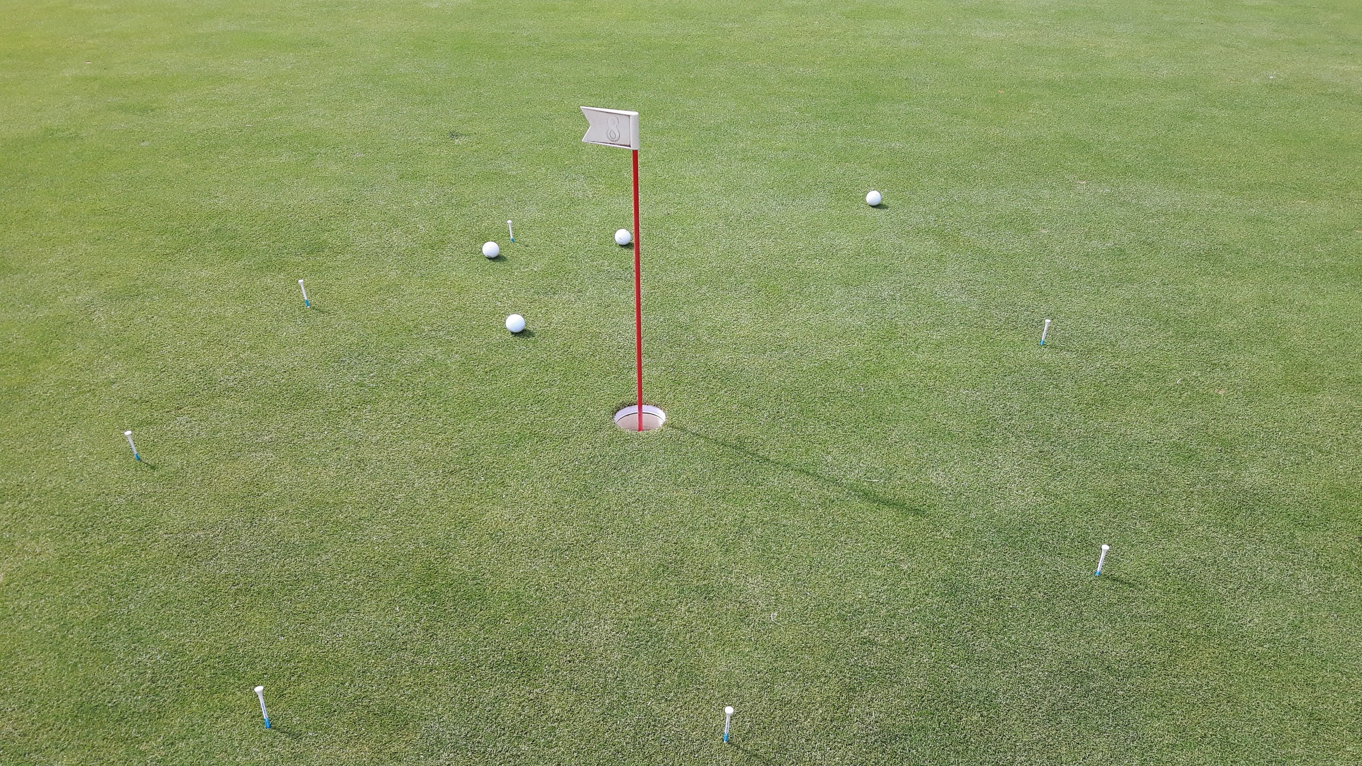 Overhead view of tees and golf balls near a hole on the course